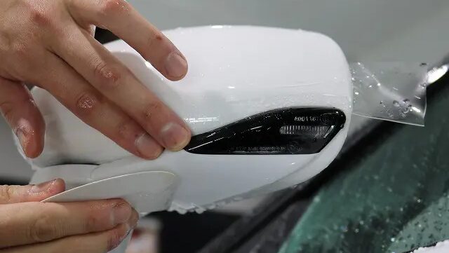 ドアミラーにプロテクションフィルムを貼っている様子
