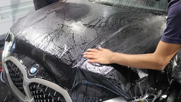 BMWのボンネットにカーボン調フィルムを合わせている様子