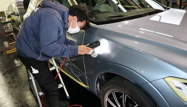 ボディの線傷をライトでチェックしている様子