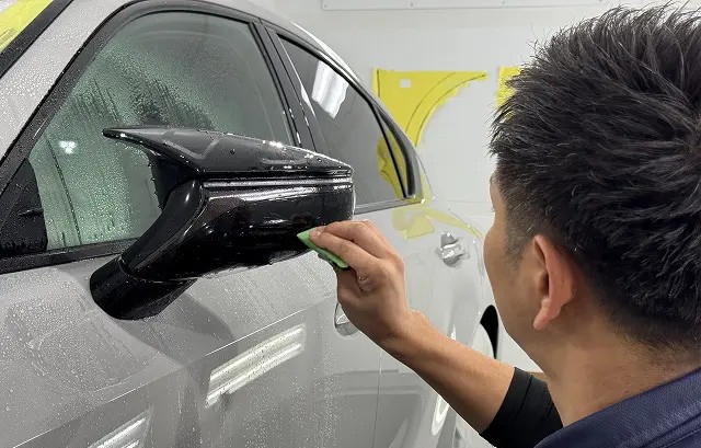 レクサスISのミラーにプロテクションフィルムを貼る様子