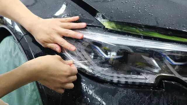BMWのヘッドライト部分にプロテクションフィルムを貼っている様子