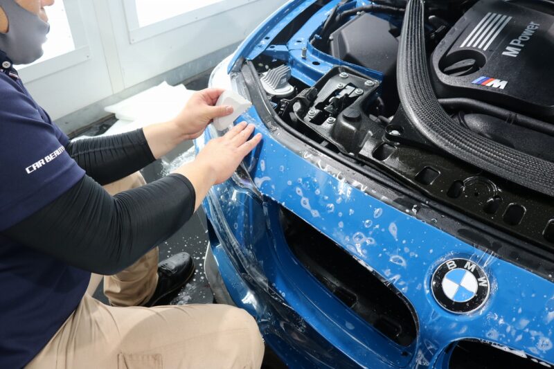 BMWのフロント部分にプロテクションフィルムを貼る様子