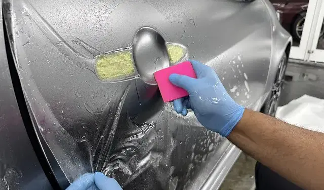 ドアハンドルにプロテクションフィルムを貼る様子