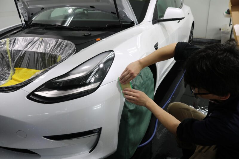 テスラモデル3にプロテクションフィルムを施工している様子