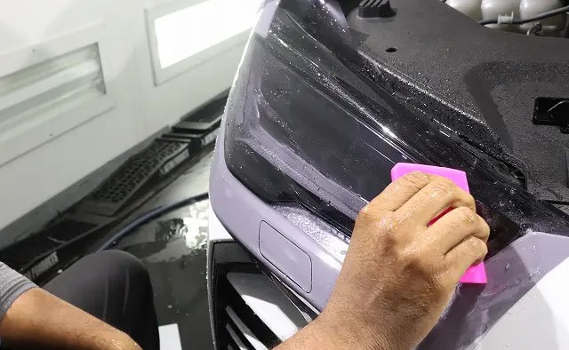 ランボルギーニ・ウルスのヘッドライトにプロテクションフィルムを施工する様子