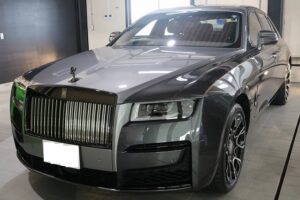 Gray luxury sedan with a tall chrome vertical-bar grille and hood ornament, displayed in a showroom bay.