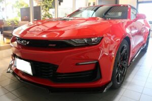 Front three-quarter view of a red Chevrolet Camaro SS in a dealership showroom.
