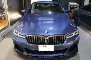 Blue BMW Alpina front view in showroom, showing the distinctive kidney grille and LED headlights.