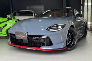 Blue Toyota Supra on a showroom floor, featuring a red front lip and black alloy wheels, with other cars in the background.