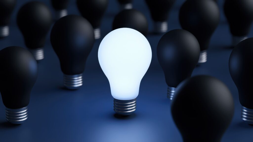 Bright white light bulb standing out among dark bulbs
