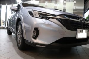 New white Subaru SUV on showroom floor, front-left angle showing sleek grille and headlights