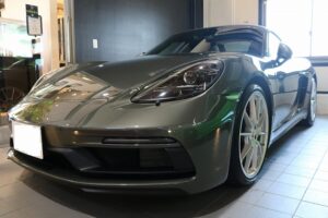 Gray Porsche sports car on showroom floor, front-left view in a dealership