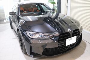 Front view of a black BMW sedan in a showroom, glossy finish and orange interior visible through the windows