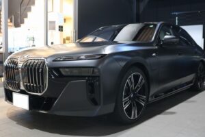Front three-quarter view of a metallic gray BMW luxury SUV on showroom floor, large kidney grille visible (indoor car dealership)