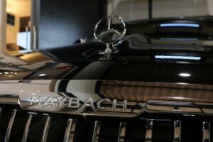 Close-up of a black Mercedes-Maybach car hood with the chrome emblem and hood ornament visible above the grille.