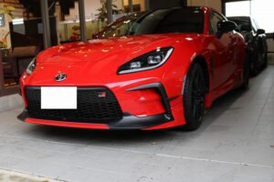 Red Toyota GR Supra sports car on a dealership showroom floor, front view with black grille and aggressive bumper.