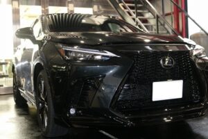 Front view of a black Lexus luxury SUV in a showroom, highlighting the bold grille and sleek headlights.
