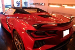 Red Chevrolet Corvette convertible in a showroom, viewed from the rear side with a spoiler and glossy red paint