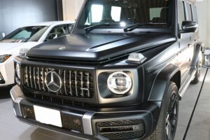 IMG_8964 - トータルカービューティIIC Front view of a black Mercedes‑Benz G-Class SUV in a showroom.