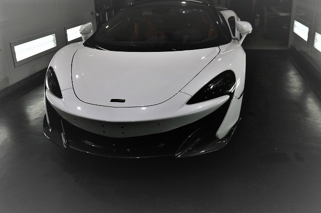 White high-performance sports car with a low, curved front, parked in a showroom bay.