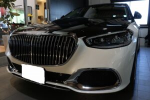 Front view of a black-and-white luxury sedan on a dealership floor with a large chrome grille and LED headlights