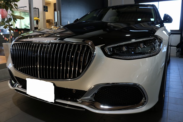 Front view of a black-and-white luxury sedan on a dealership floor with a large chrome grille and LED headlights